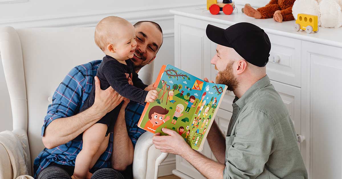 two gay fathers playing with their child