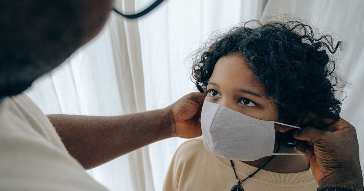 man putting medical mask on face of child during child custody visitation to prevent getting COVID-19