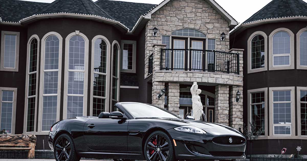 expensive sports car parked in front of mansion