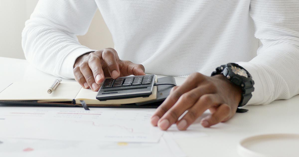 man using a calculator with documents spread over a table