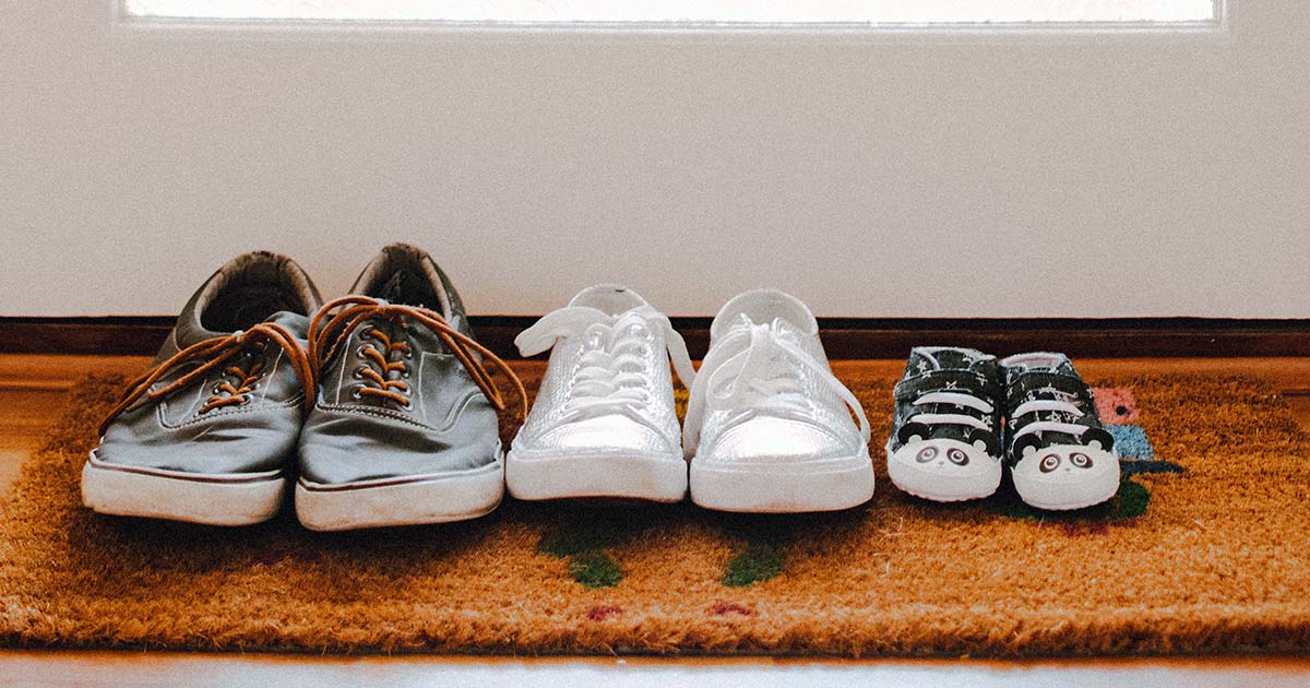 adult shoes and child shoes lined up on door mat