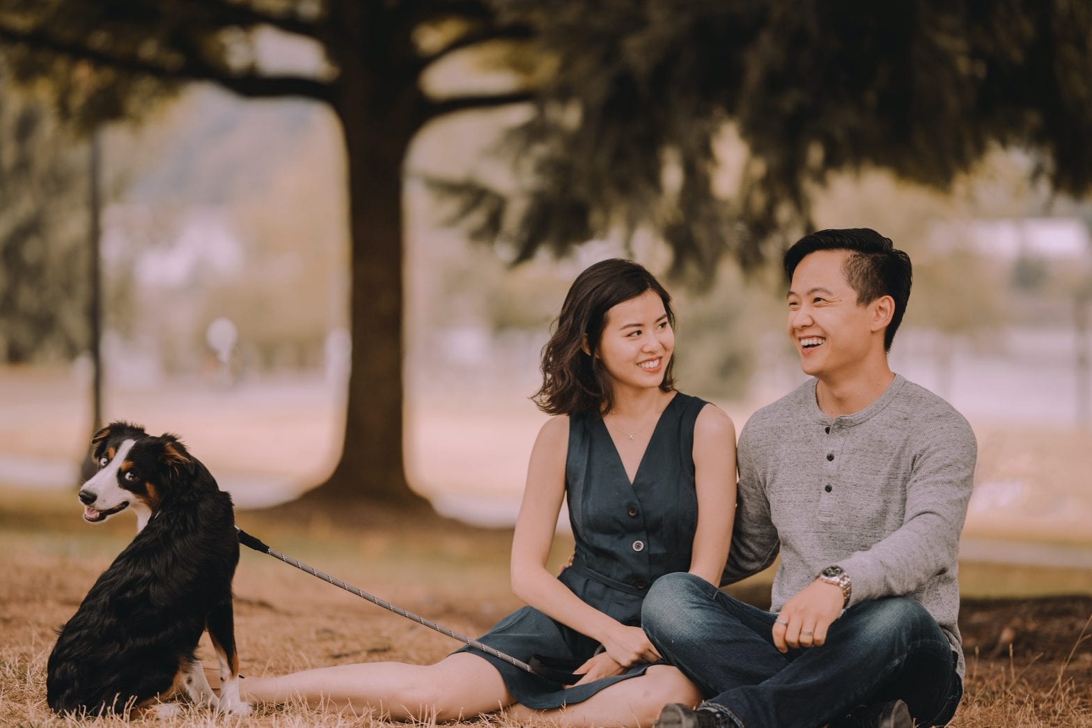 Content Asian couple with dog resting in urban park