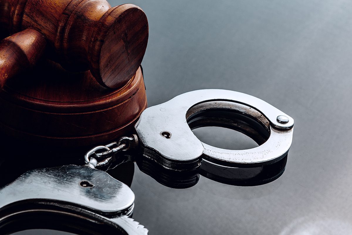 Judge mallet and handcuffs on black background close up