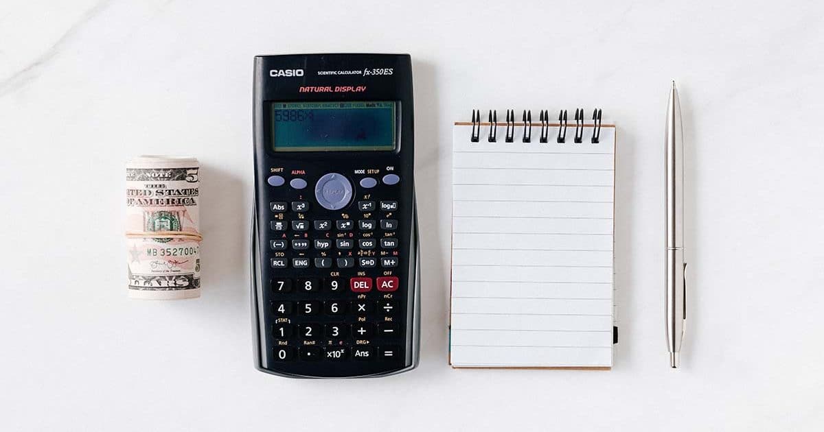 Composition of calculator with paper money and notebook with pen