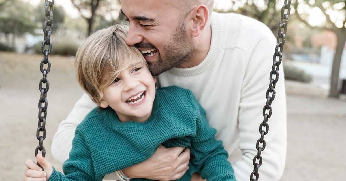 father and son having fun on city park swing