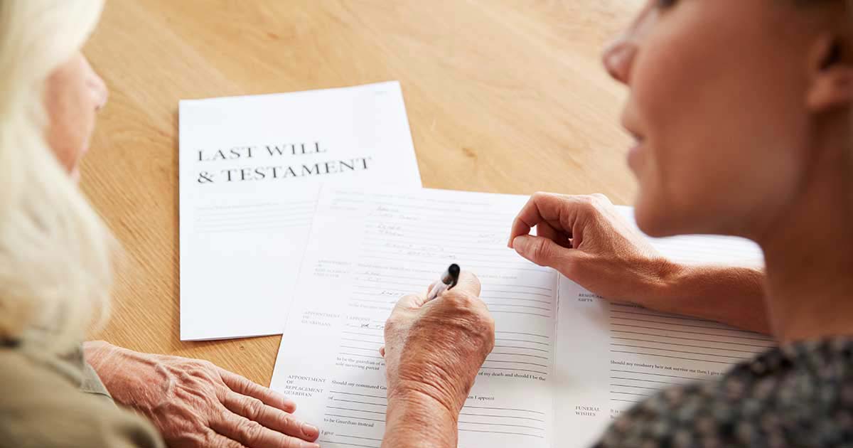 younger woman helping senior woman sign her Last Will and Testament which can avoid probate litigation