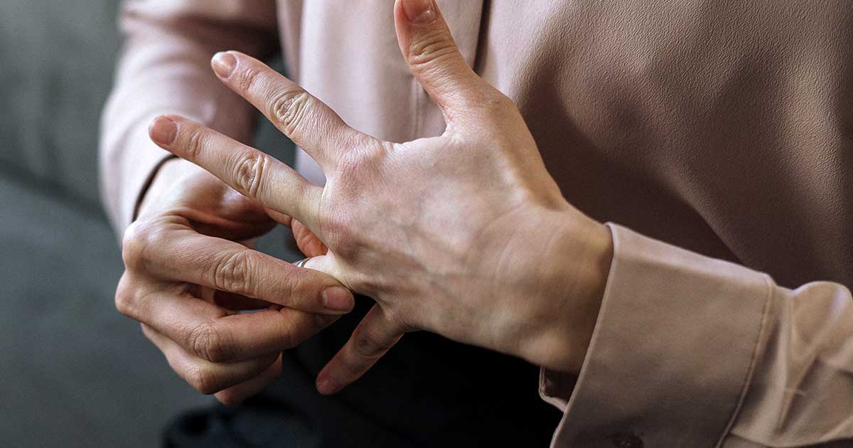 woman removes a gold wedding ring from her finger