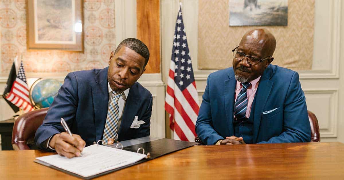 A Man Signing his Will and Living Trust documents beside his lawyer