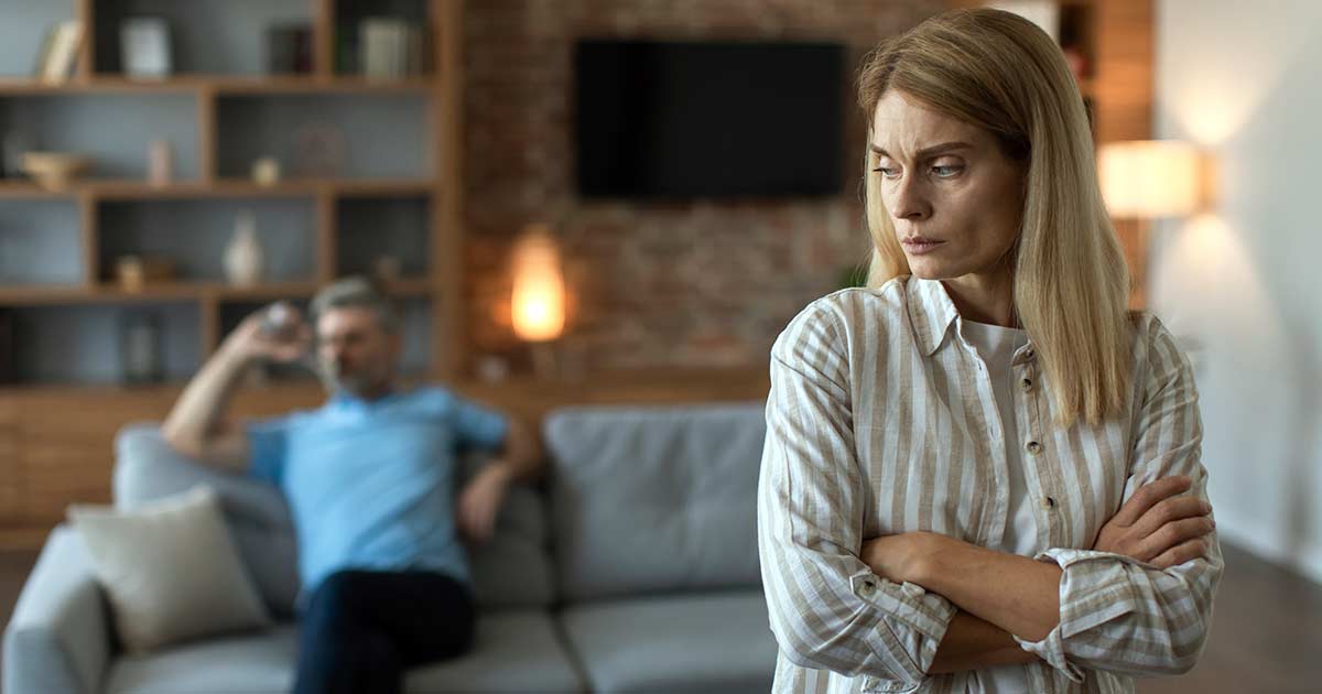 Upset offended middle aged caucasian wife ignores angry sad husband in living room interior