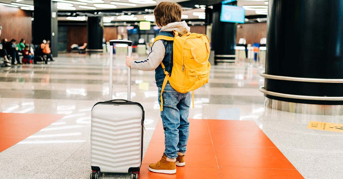 Child, boy with backpack and suitcase in airport