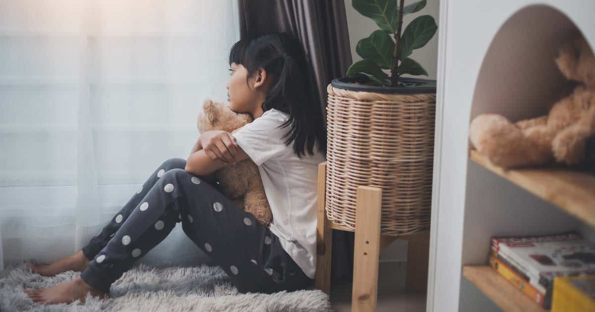 Close up lonely little girl hugging toy, sitting at home alone, upset unhappy child waiting for parents, thinking about problems, bad relationship in family, psychological trauma