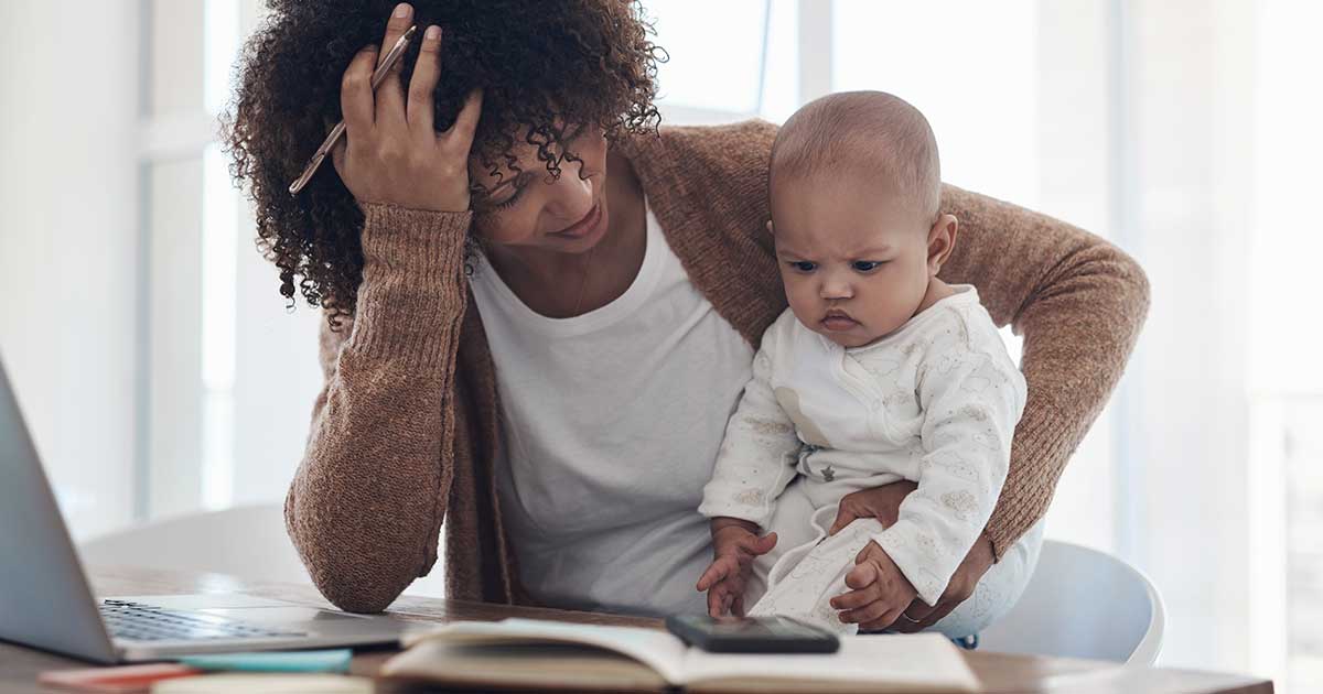 Shot of a young woman looking stressed while caring for her adorable baby girl and working at home