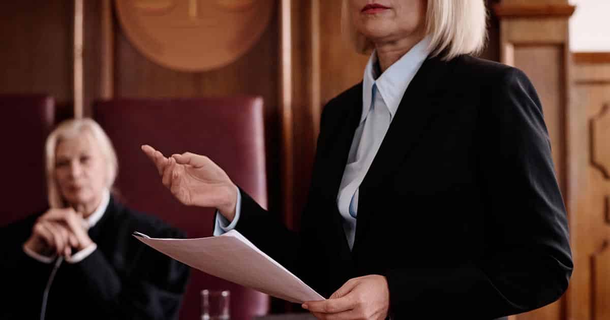 Confident female lawyer with juridical document standing in front of judge
