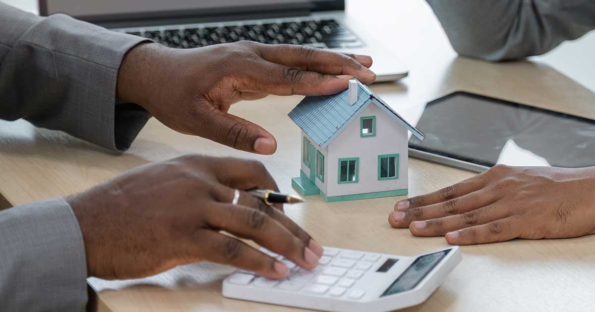 two person having a meeting where a toy house on an office desk; real estate concept